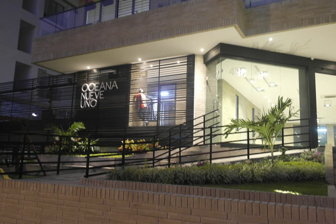 La entrada al anochecer, con el nombre del edificio encendido.