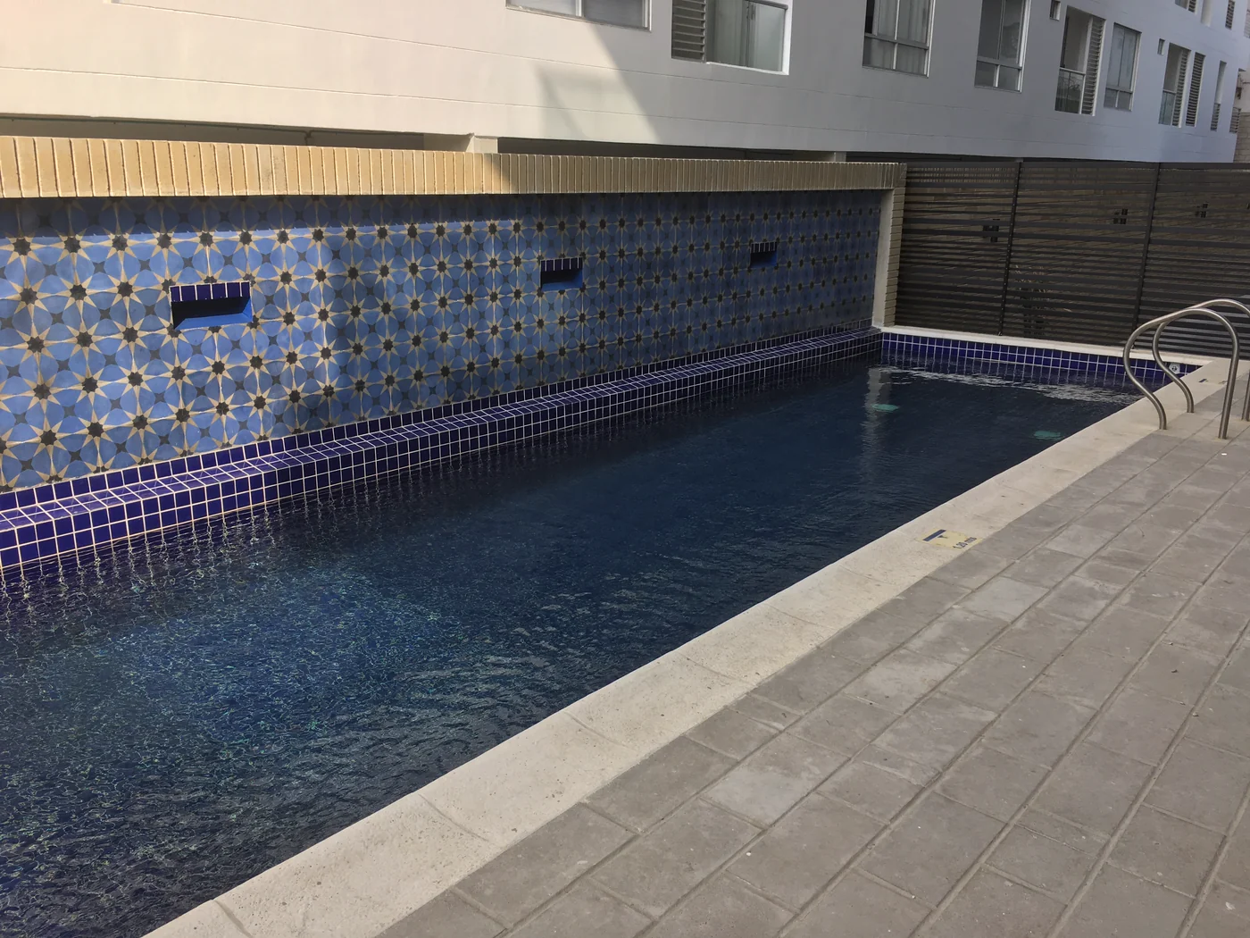 La piscina, con el muro de mosaico azul al fondo.